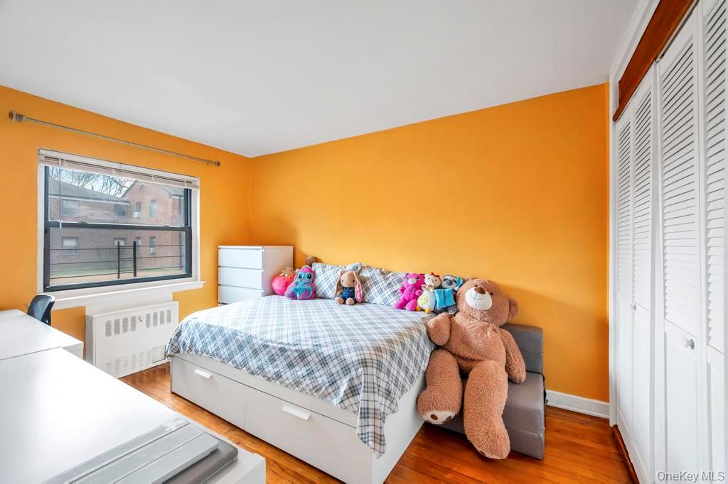 196-72 69th Avenue, Unit 1 Queens, NY 11365 - Photo 16 of 23 Bedroom featuring radiator heating unit, a closet, and wood finished floors
