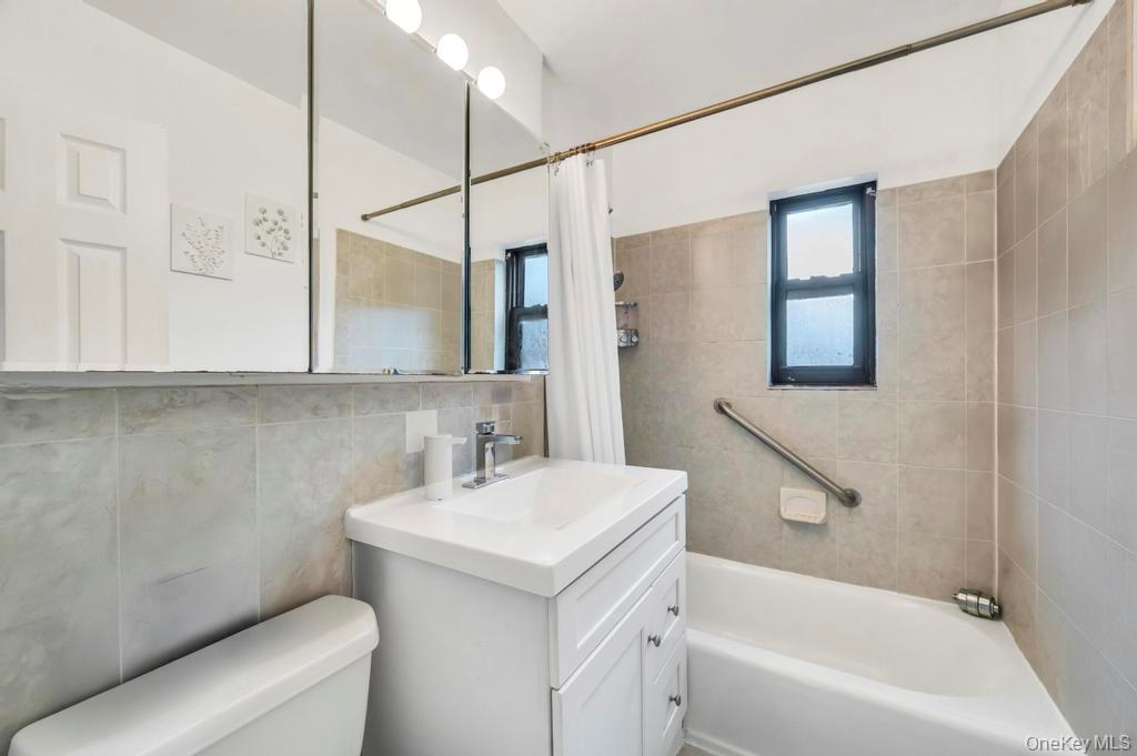 196-72 69th Avenue, Unit 1 Queens, NY 11365 - Photo 17 of 23 Bathroom featuring vanity, shower / bath combination with curtain, and tile walls