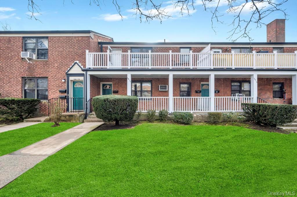 196-72 69th Avenue, Unit 1 Queens, NY 11365 - Photo 2 of 23 Traditional-style house featuring brick siding, a front lawn, covered porch, and a balcony