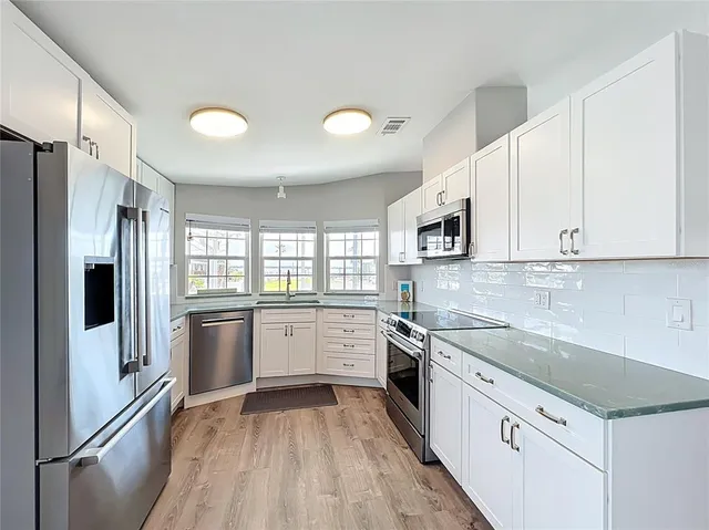 a kitchen with granite countertop white cabinets and window