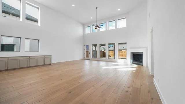 a view of empty room with wooden floor and kitchen view