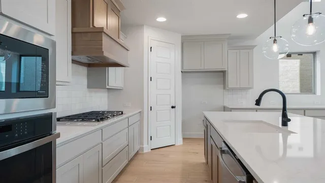 a kitchen with stainless steel appliances a sink a stove and cabinets