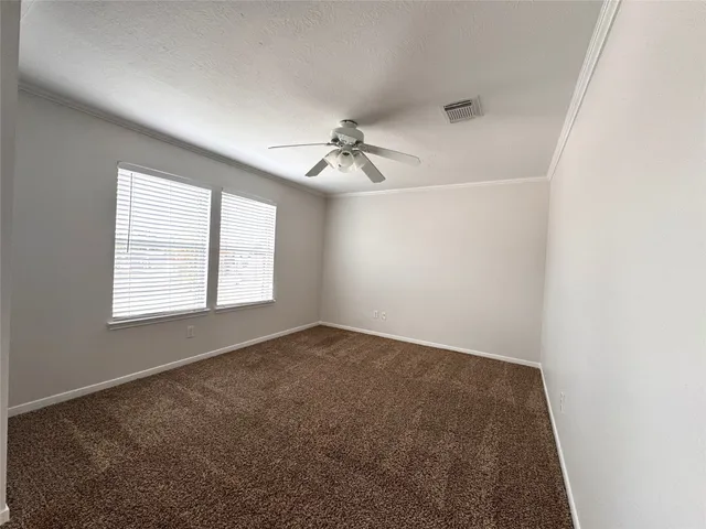 an empty room with windows and chandelier fan
