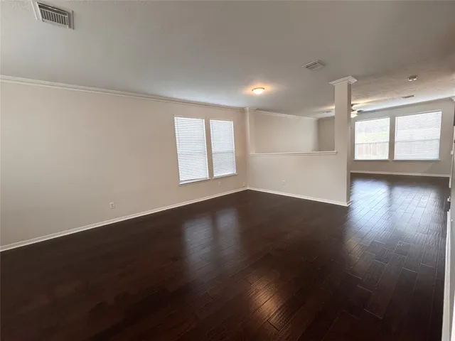 an empty room with wooden floor and windows