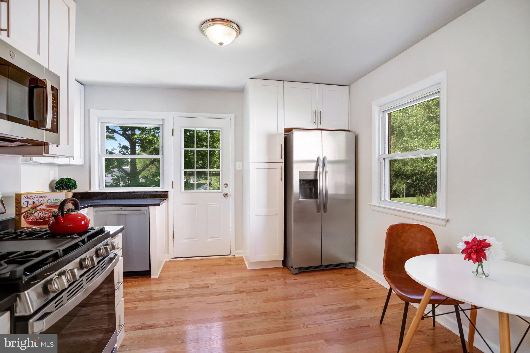 616 Ritchie Avenue Silver Spring, MD 20910 - Photo 13 of 37 a kitchen with stainless steel appliances granite countertop a refrigerator a stove a sink dishwasher and a dining table with wooden floor
