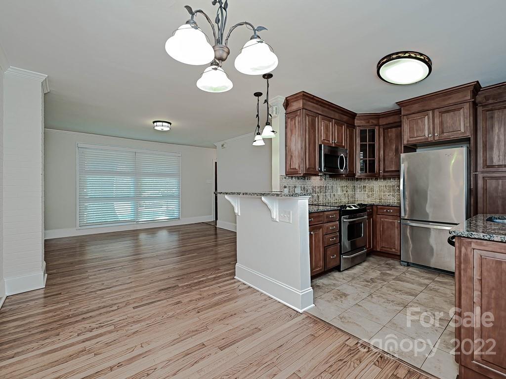 4212 Randolph Road Charlotte, NC 28211 - Photo 13 of 23 a kitchen with stainless steel appliances granite countertop a refrigerator a sink dishwasher a stove with wooden floor and cabinets