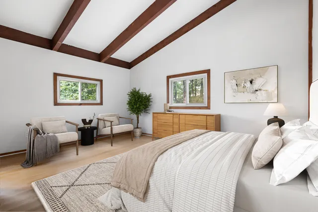 a bedroom with a large bed couch and two windows