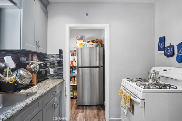 a kitchen with granite countertop a sink a stove and cabinets
