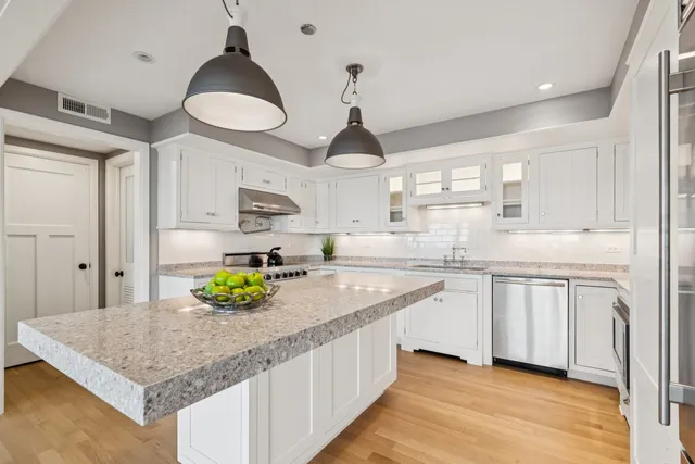 a kitchen with stainless steel appliances granite countertop a sink a stove and a wooden floors