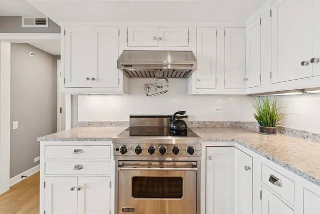 a kitchen with stainless steel appliances granite countertop a stove and a wooden floors