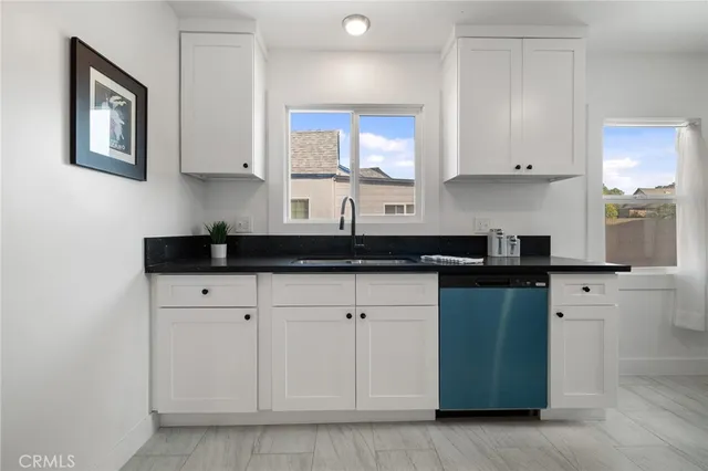 a kitchen with white cabinets a sink and dishwasher