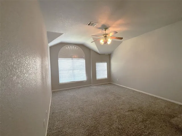an empty room with windows and ceiling fan