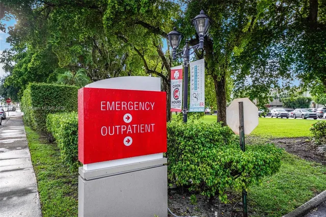 a view of sign board with buildings and cars parked in front of it