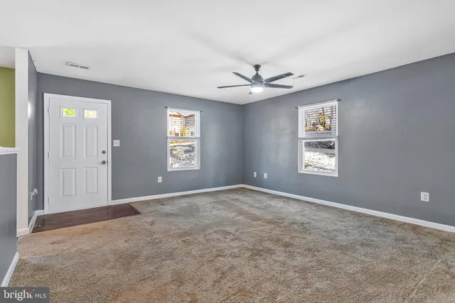 an empty room with windows and fan