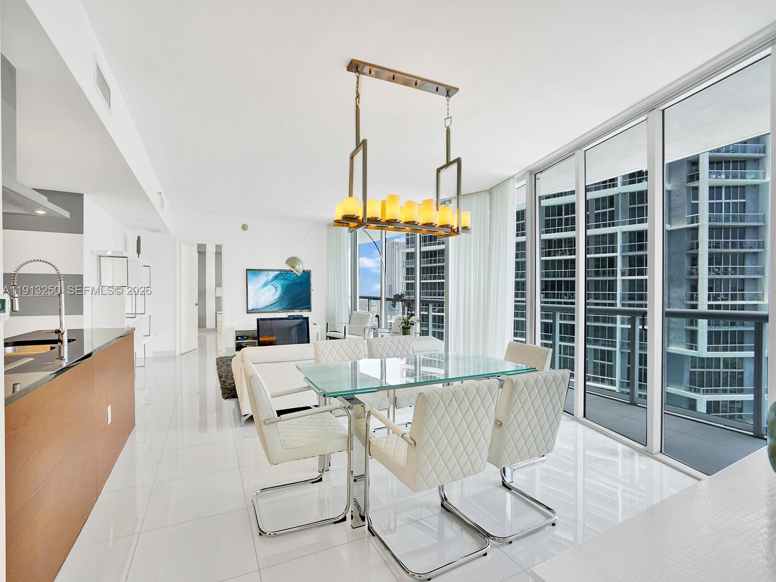 495 Brickell Avenue, Unit 2504 Miami, FL 33131 - Photo 13 of 28 a living room with furniture a chandelier and a floor to ceiling window