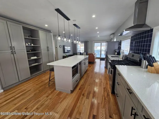 a large kitchen with stainless steel appliances kitchen island granite countertop a large counter top a stove a chimney a sink and a refrigerator