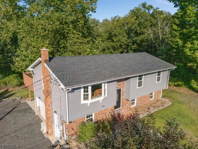aerial view of a house with yard and trees in the background