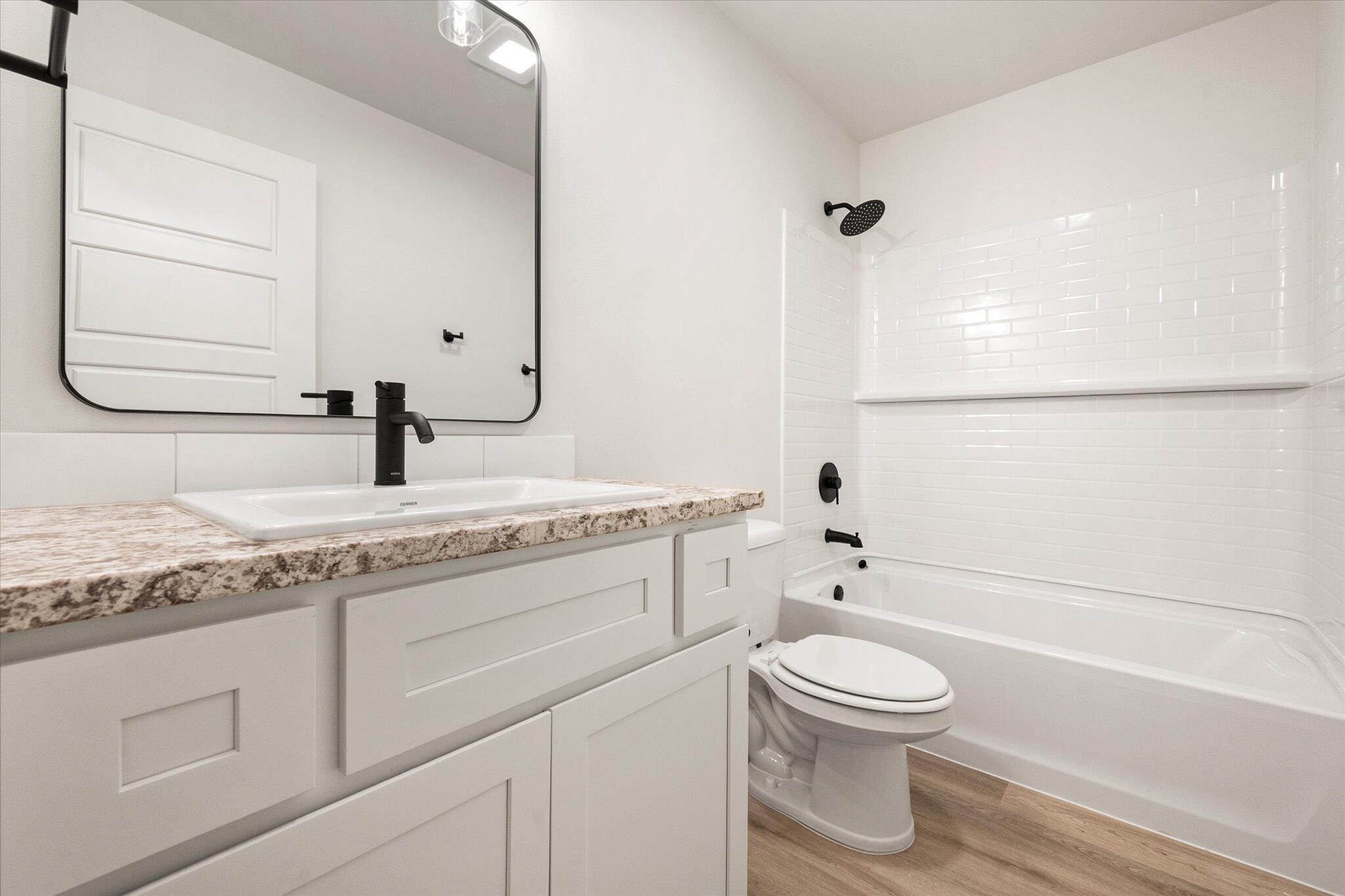 7214 8th Street Lubbock, TX 79416 - Photo 19 of 23 a bathroom with a granite countertop toilet a sink and a bathtub