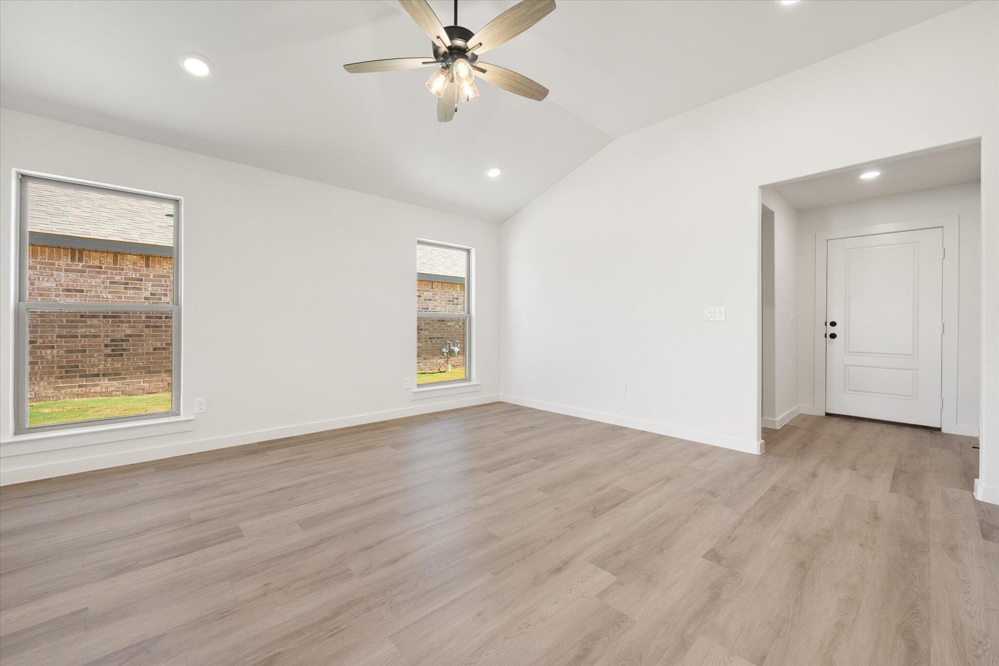 7214 8th Street Lubbock, TX 79416 - Photo 6 of 23 an empty room with wooden floor chandelier fan and windows