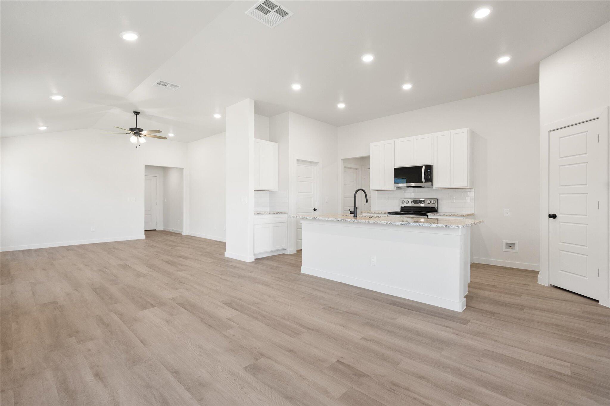 7214 8th Street Lubbock, TX 79416 - Photo 10 of 23 a view of kitchen with kitchen island a sink wooden floor and stainless steel appliances