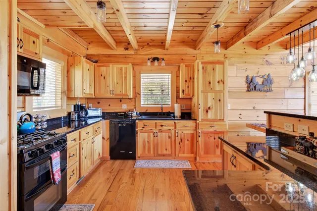 a kitchen with stainless steel appliances granite countertop a stove a sink dishwasher and white cabinets with wooden floor