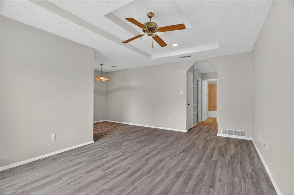 119 Del Rio Avenue, Unit C Benbrook, TX 76126 - Photo 3 of 17 an empty room with wooden floor ceiling fan and windows