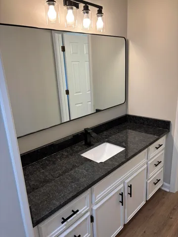 a bathroom with a granite countertop sink and a mirror