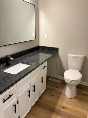 a bathroom with a granite countertop toilet sink and mirror