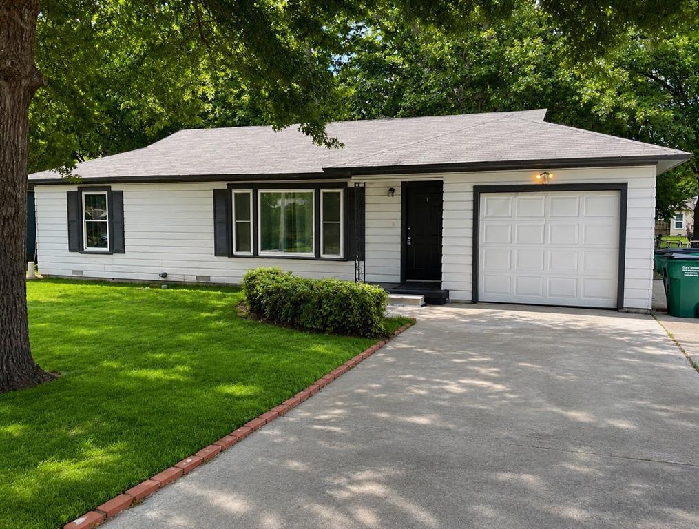 1109 North Howeth Street Gainesville, TX 76240 - Photo 1 of 11 White siding exterior with a dark trim, featuring a single-panel garage door and a concrete driveway