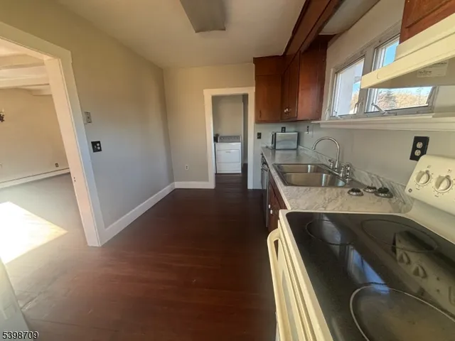 a kitchen with a sink a stove and wooden floor