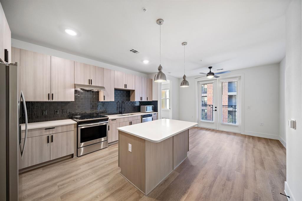 a large kitchen with stainless steel appliances granite countertop a lot of counter space and wooden floor