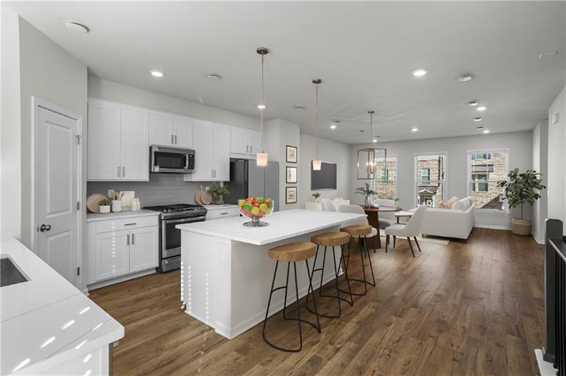 a open kitchen with stainless steel appliances kitchen island granite countertop a stove top oven a sink a dining table and chairs with wooden floor