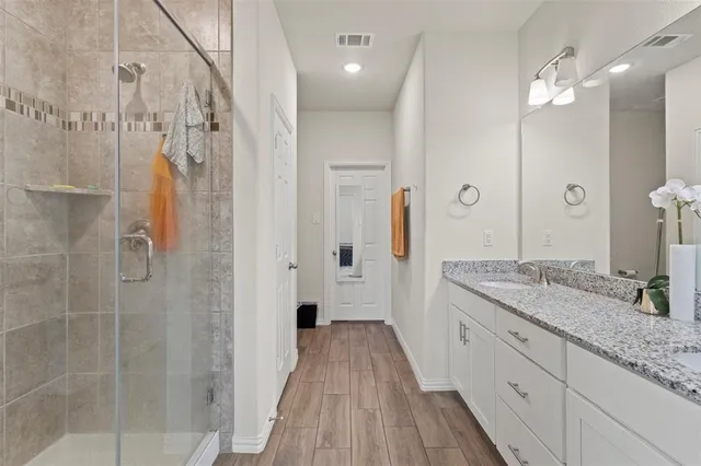a spacious bathroom with a granite countertop sink a mirror and shower