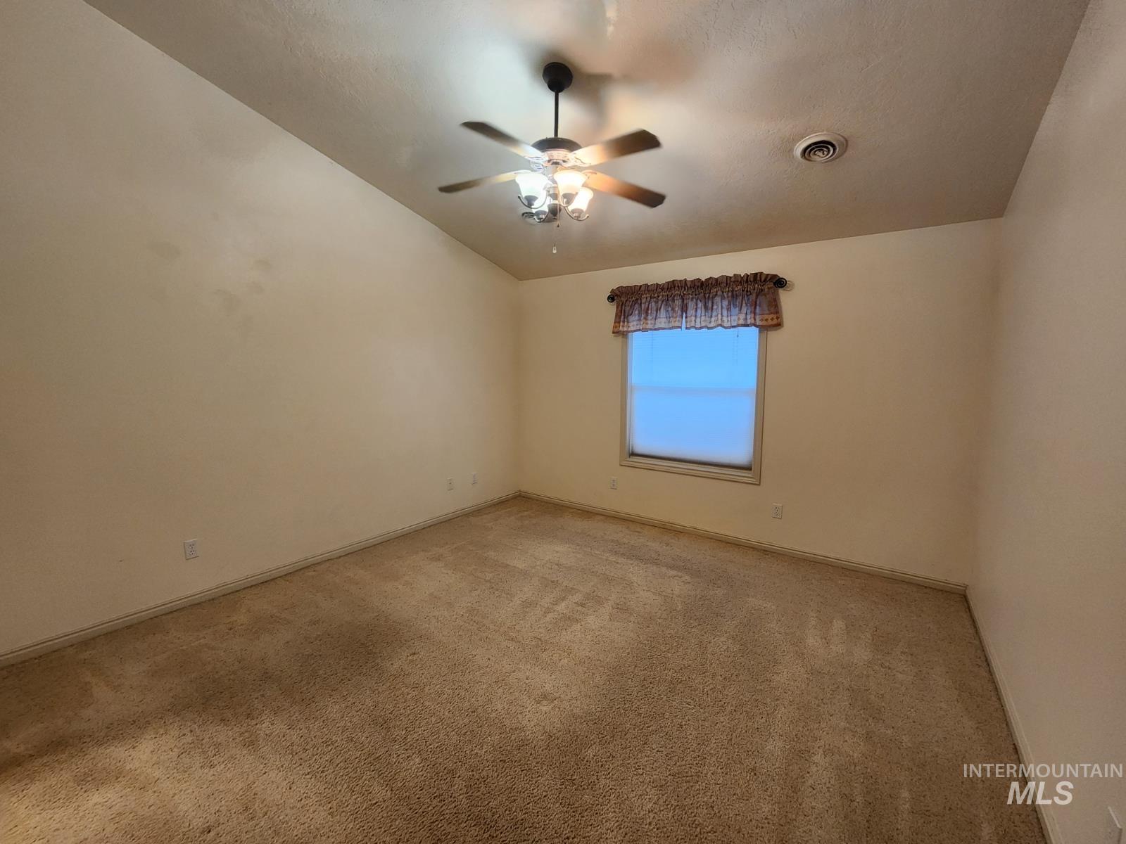 1000 North Rodeo Street Parma, ID 83660 - Photo 12 of 35 Spare room with lofted ceiling, ceiling fan, and light colored carpet