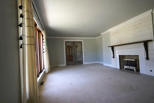 an empty room with windows and fireplace