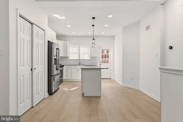 a kitchen with kitchen island wooden cabinets and refrigerator