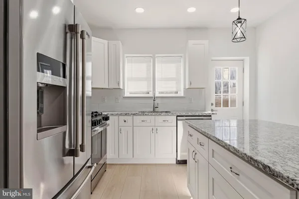 a kitchen with granite countertop a sink stove and refrigerator