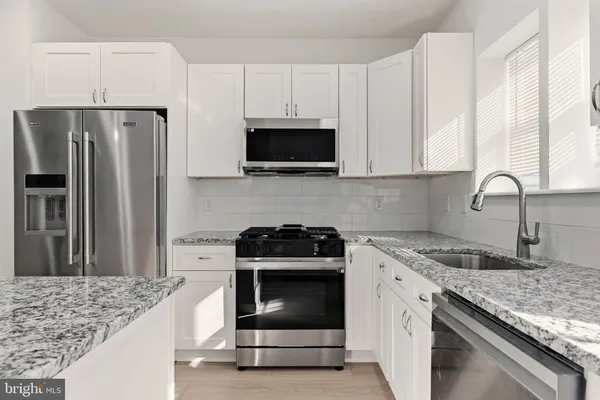 a kitchen with granite countertop a sink stove and refrigerator