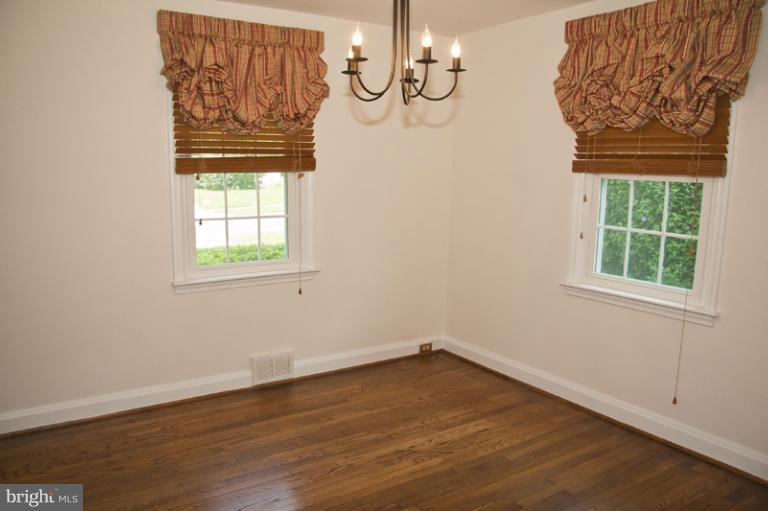 703 Sudbrook Road Pikesville, MD 21208 - Photo 4 of 15 an empty room with wooden floor and windows