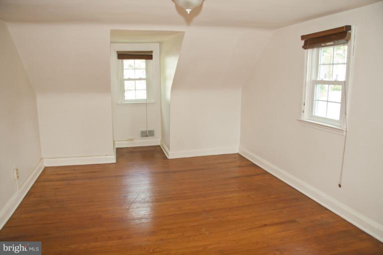 703 Sudbrook Road Pikesville, MD 21208 - Photo 6 of 15 an empty room with wooden floor and windows