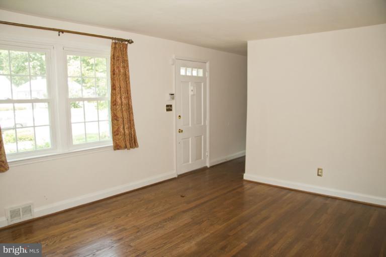 703 Sudbrook Road Pikesville, MD 21208 - Photo 8 of 15 an empty room with wooden floor and windows