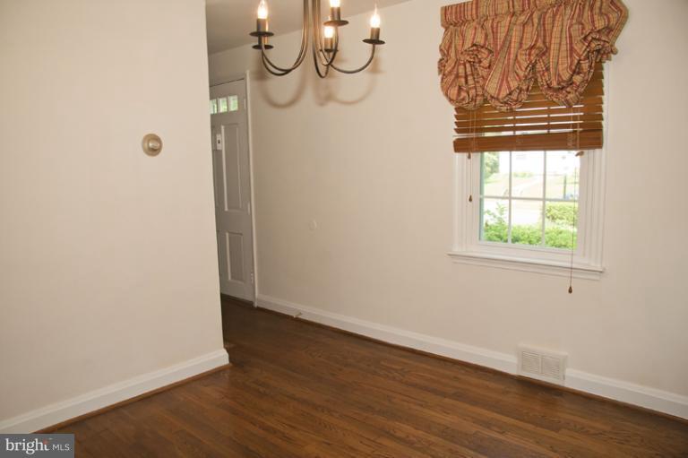 703 Sudbrook Road Pikesville, MD 21208 - Photo 9 of 15 an empty room with wooden floor and windows