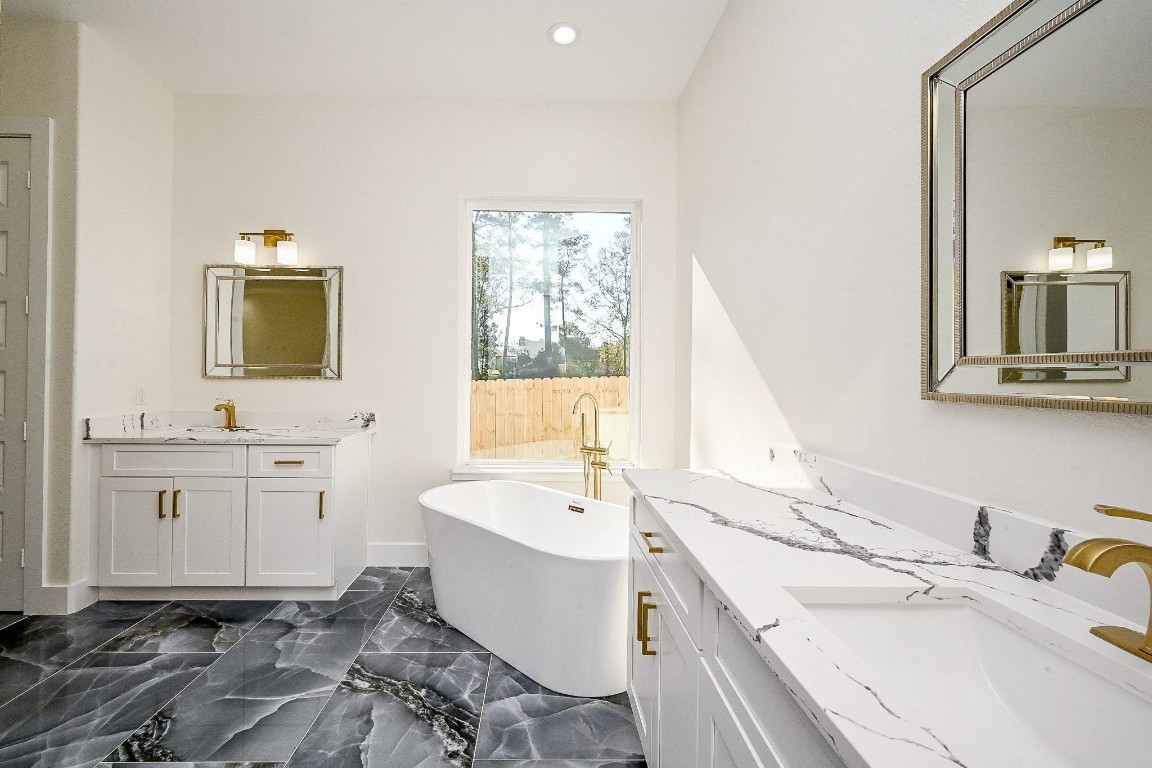 21614 Lee Road Humble, TX 77338 - Photo 20 of 36 a bathroom with a granite countertop sink mirror and a bathtub
