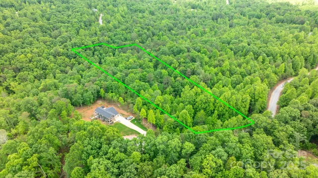 an aerial view of residential house with outdoor space and trees all around