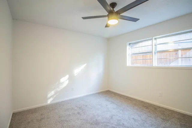 an empty room with a window and a ceiling fan