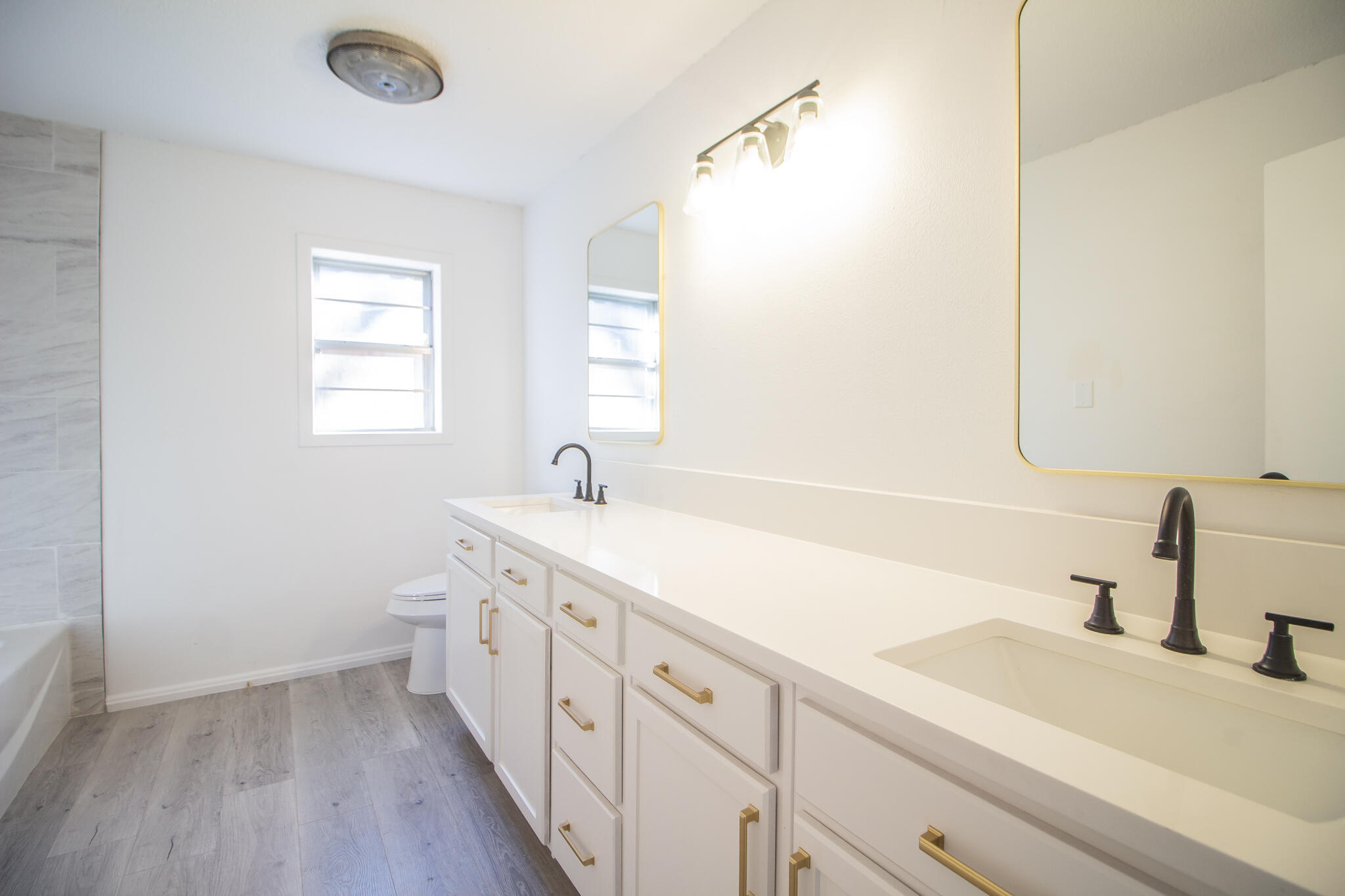 3602 63rd Drive Lubbock, TX 79413 - Photo 23 of 33 a bathroom with a double vanity sink a mirror and a bathtub