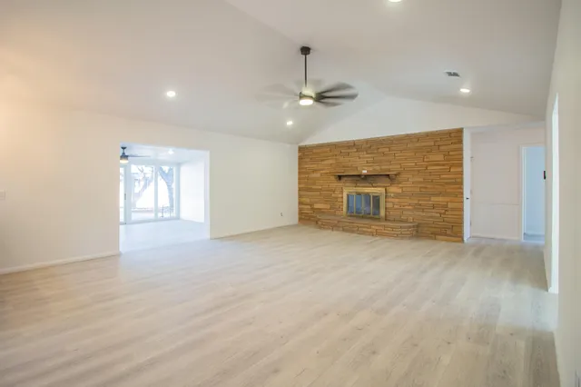 an empty room with windows and fireplace