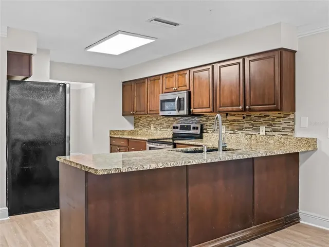 a kitchen with stainless steel appliances granite countertop a refrigerator a stove a sink and a microwave
