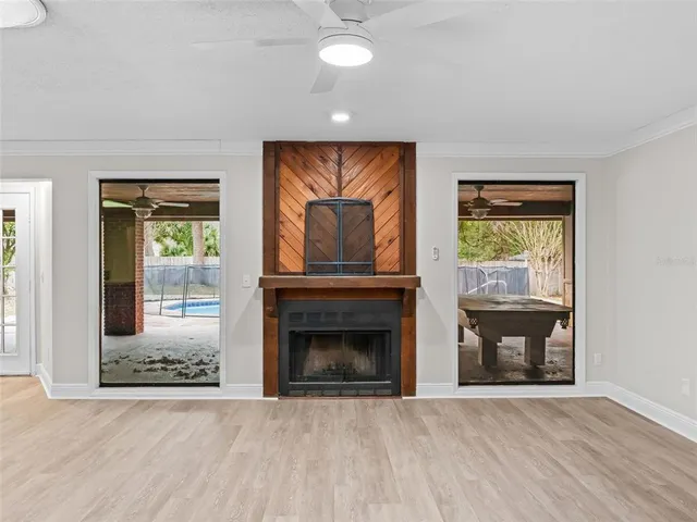 a view of an empty room with wooden floor fireplace and a window