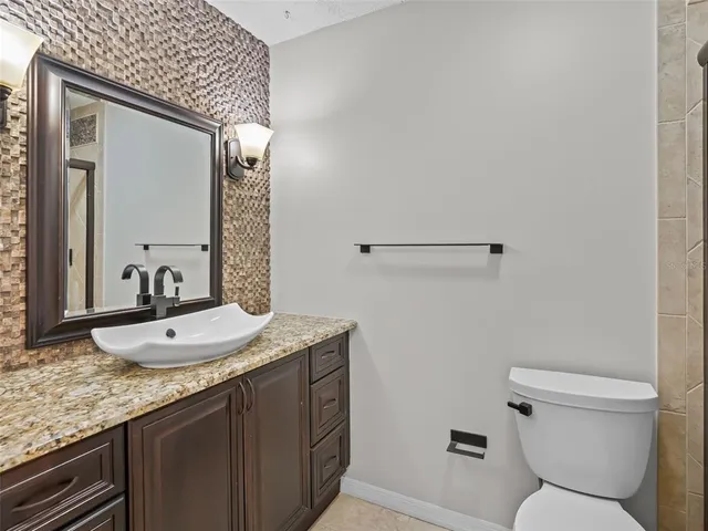a bathroom with a granite countertop sink a toilet and a mirror